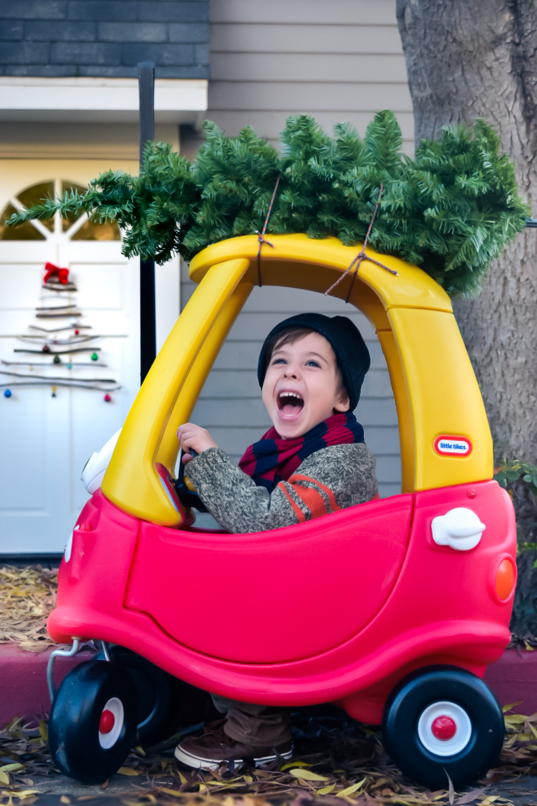 a boy in a toy car with xmas tree